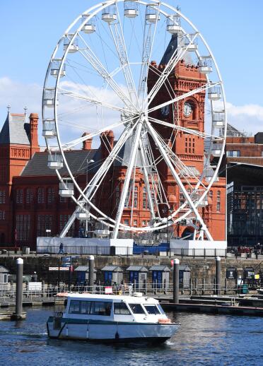 Big wheel in front of the Pier Head building in a city bay.