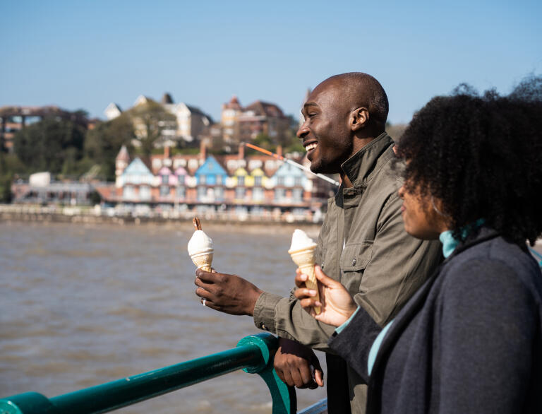 A couple eating ice cream by the sea.
