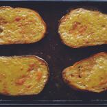 Slices of Welsh rarebit on a baking tray.
