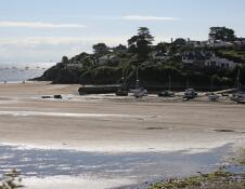 Abersoch harbour with boats and yachts moored on the beach with the tide out.