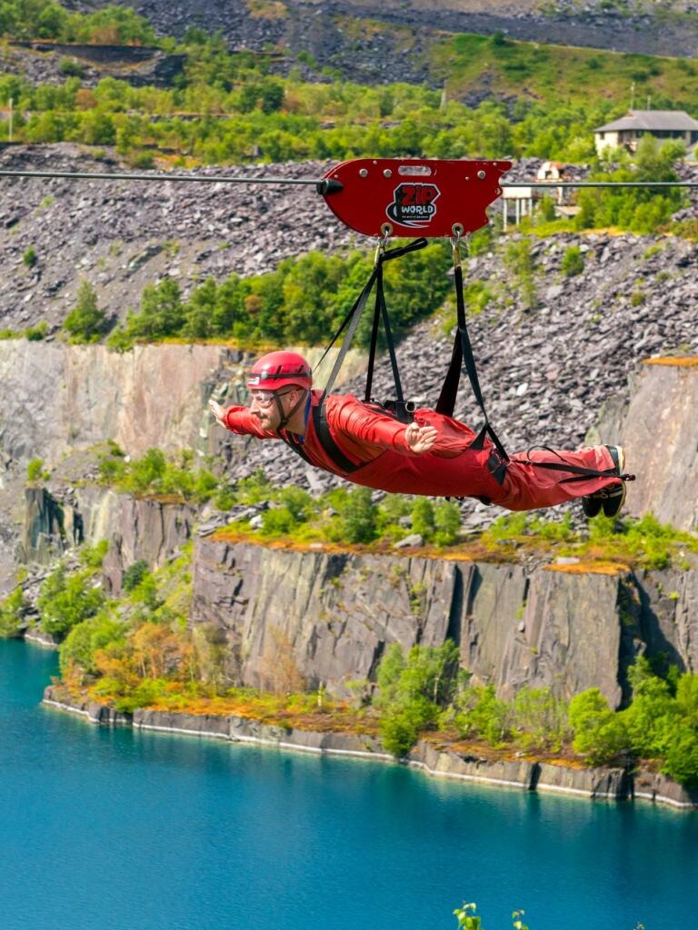 Man on zip wire ride above lake.