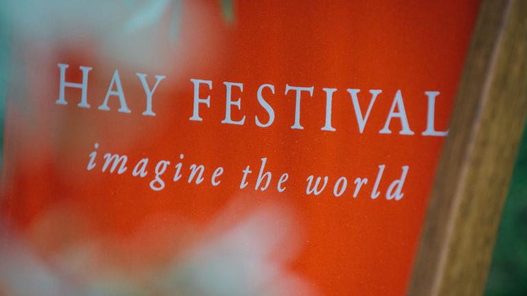Red deckchair with 'HAY FESTIVAL imagine the world' in white type.