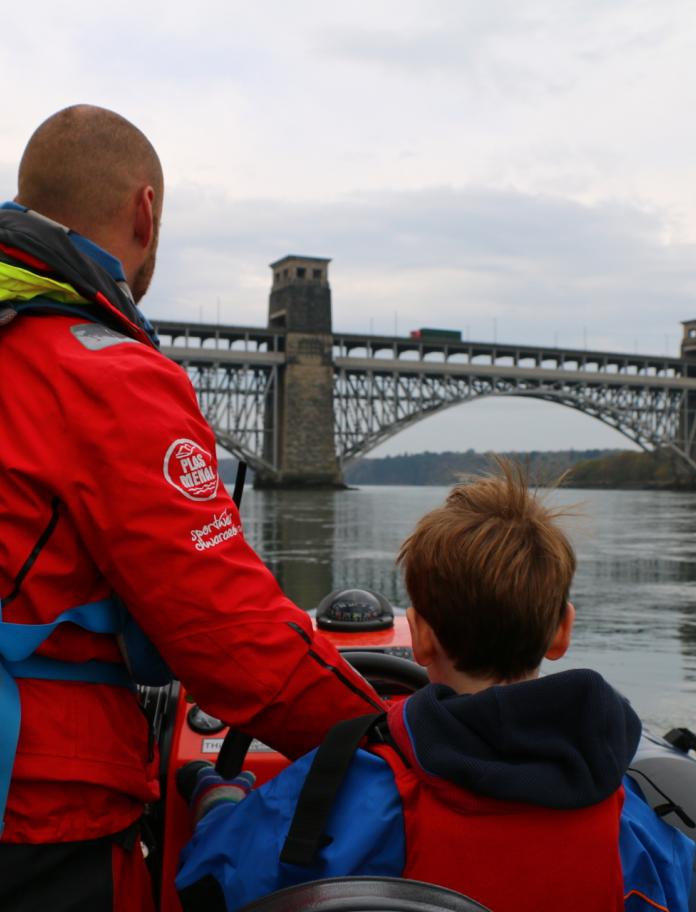 Man and a boy on a speedboat on the Menai Strait.
