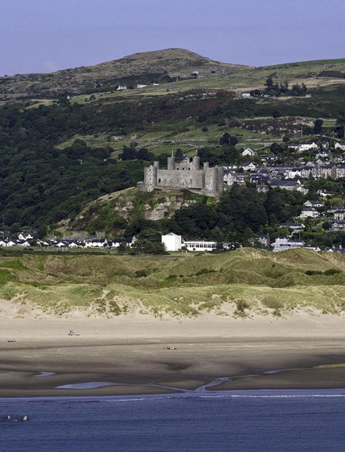 Blick auf einen Strand vom Meer aus mit einer Burg im Hintergrund.