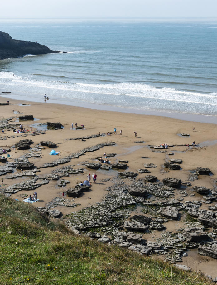 A busy sandy beach with rockpools and cliffs.