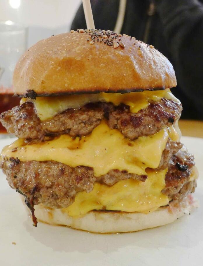 A massive bacon and cheese burger on a table.