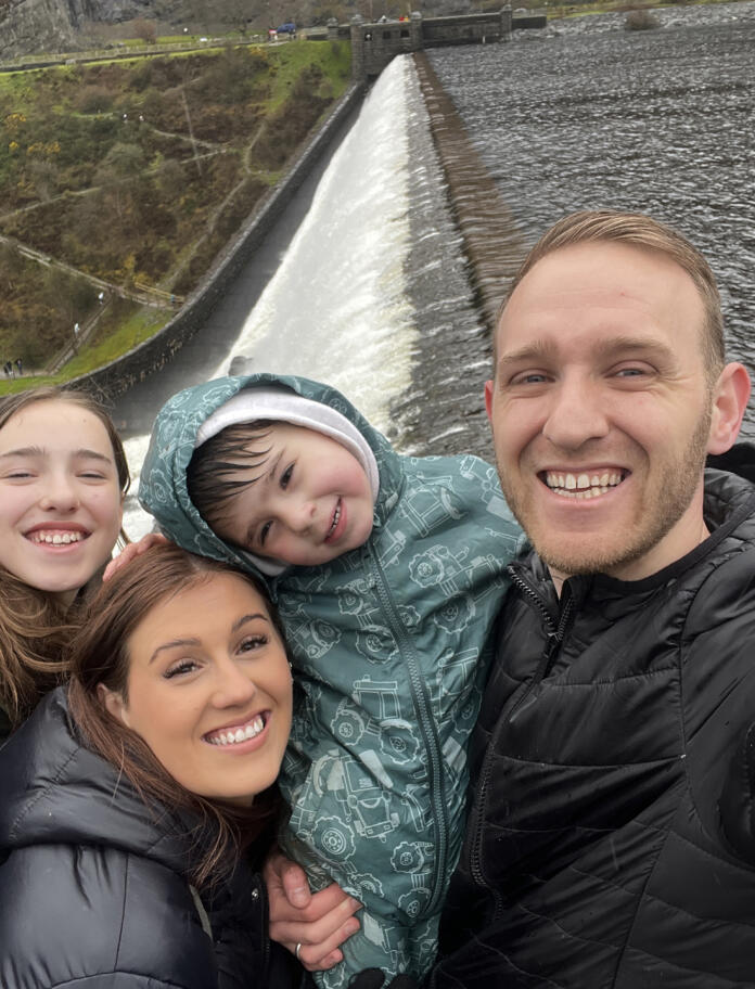 Two adults and two children taking a selfie at the side of an overflowing dam.