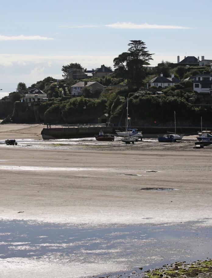 Abersoch harbour with boats and yachts moored on the beach with the tide out.