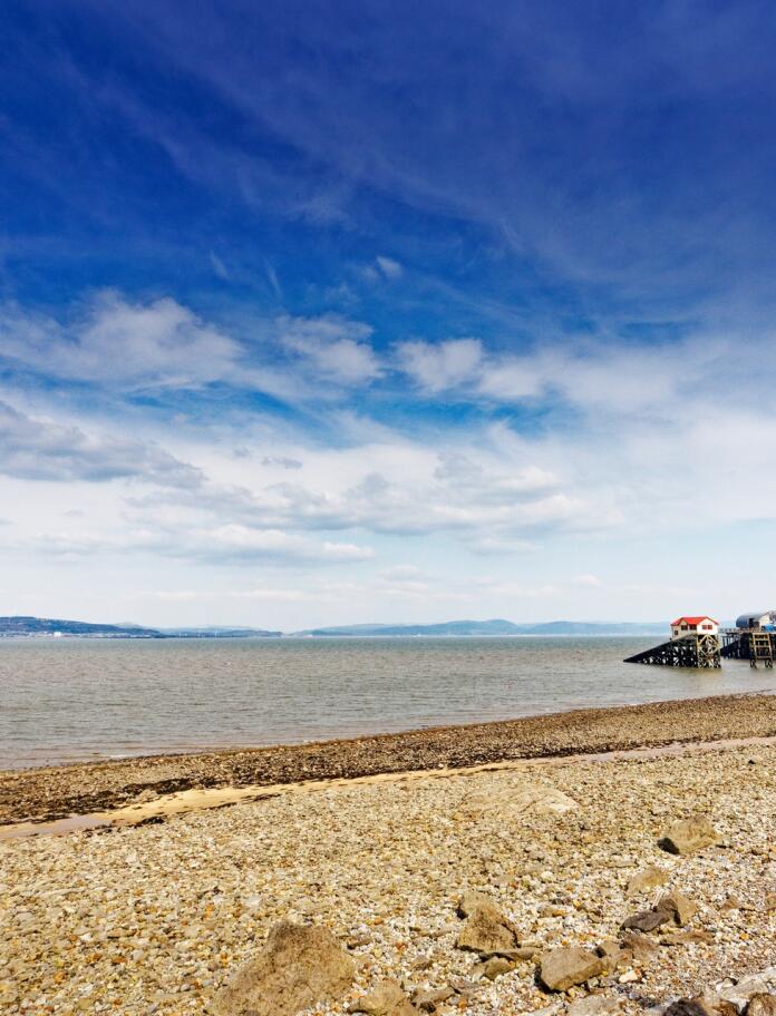 A pebbly beach and a pier. 