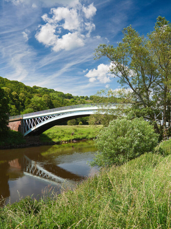 Bigsweir Bridge spanning the River Wye with grass and trees on the river banks.