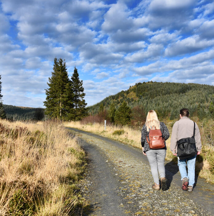 Two women walking along a gravel pathway up a hillside.