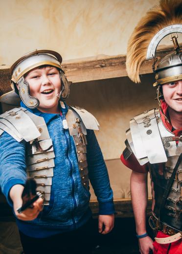 Two children dressing up in Roman armour.
