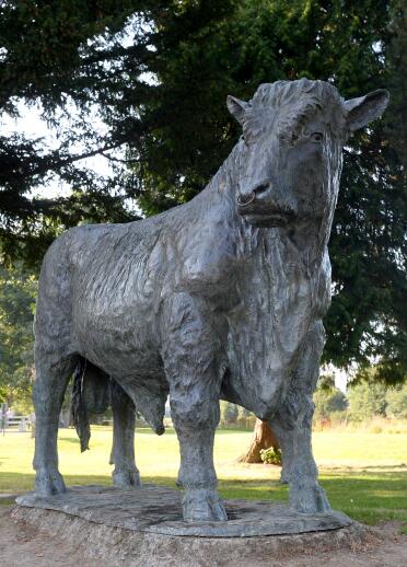 Metal sculpture of a bull in a park.