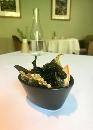 A small bowl of crispy green leaves and crackers. 