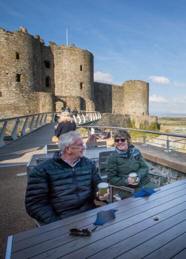 Ein älteres Paar trinkt Kaffee zum Mitnehmen vor einer Burg und genießt die Aussicht