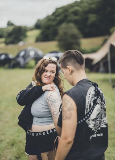 Two people at a festival, one showing off a new tattoo on their arm