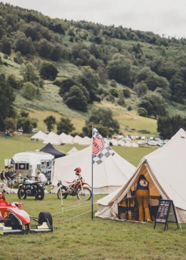 Bell tents and motorbikes at a lush green festival site