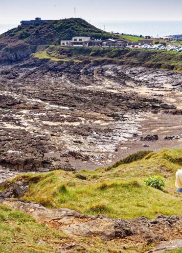 A rocky bay by the sea, fringed with low cliffs and parking spots. 