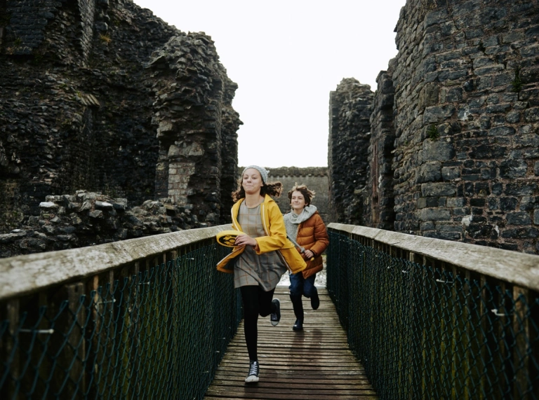 Two children running across a footbridge straight towards the camera