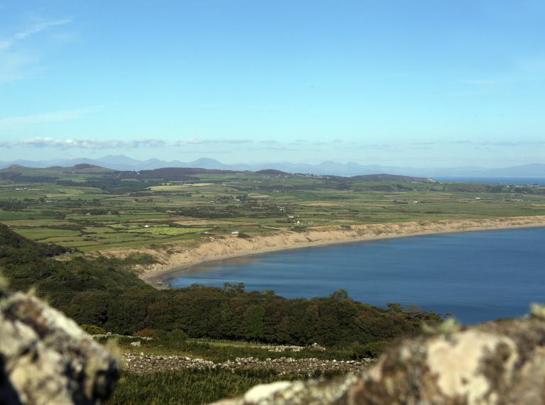 A wide, curved sandy beach seen from high ground.