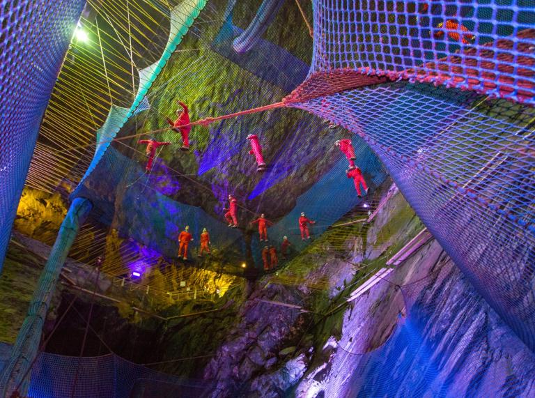 Group of people bouncing in a net in an underground cavern.