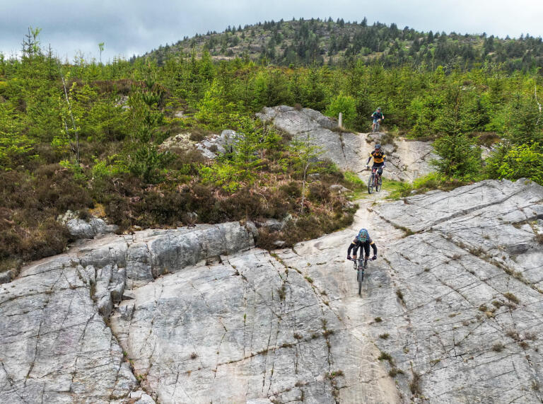 Mountain bikers riding on a rock slab trail in the hills.