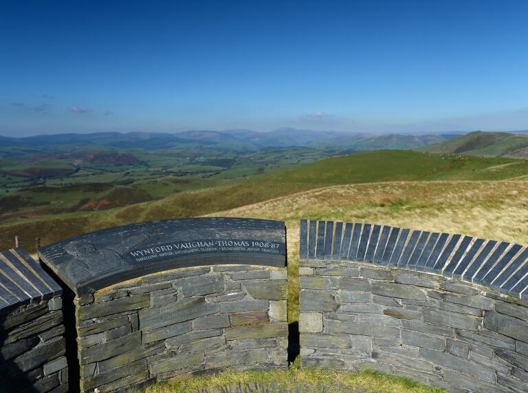 The view from a slate memorial on a hillside, looking over miles of rolling hills. 
