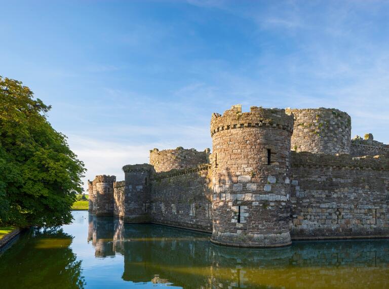 Side view of Castell Biwmares (Beaumaris Castle) with water and blue sky.