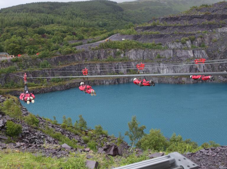 Four people on Zip World Velocity over Penrhyn Quarry lake.
