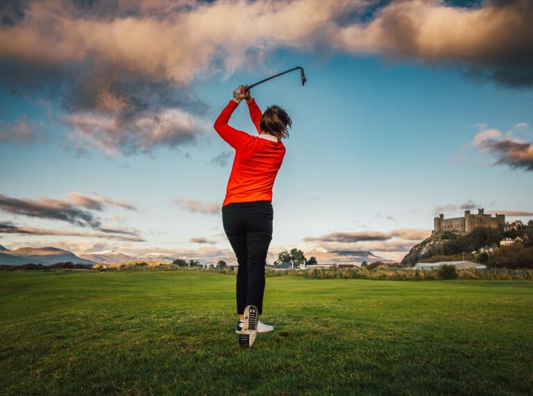female golfer swings club.