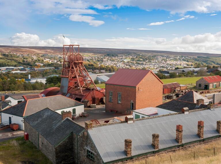 View of the Big Pit winding tower and outbuildings with the town in the background