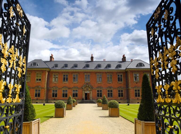 red 17th century manor through open gates.