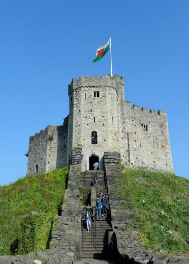 People walking up steps leading up to a castle keep on a hill.