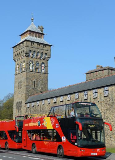Ein offener Sightseeing-Bus vor dem Cardiff Castle mit dem Glockenturm im Hintergrund.tower.