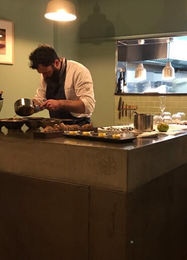 Ein Chefkoch präpariert Essen an einer Kücheninsel mitten in einem Restaurant.