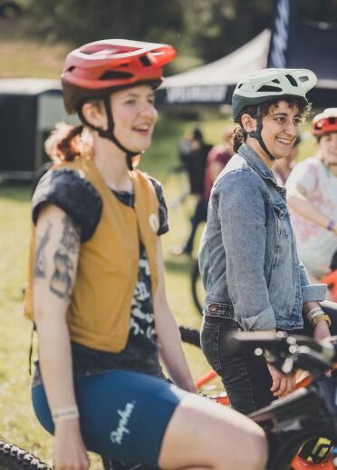 A group of smiling, happy womxn on mountain bikes at a festival 