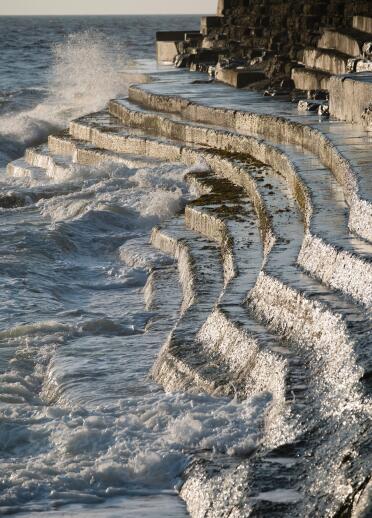 waves crashing on to stone steps on Aberystwyth seafront.