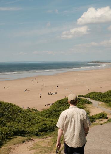 man and Whippet dog near sandy beach.