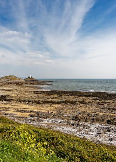 A rocky beach with a lighthouse at one end.