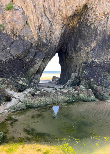 A tunnel through a cliffside on a beach.