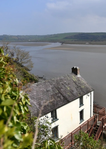 A white boathouse looking over the estuary.