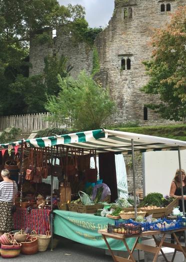 market stalls with people shopping in foreground with castle in background