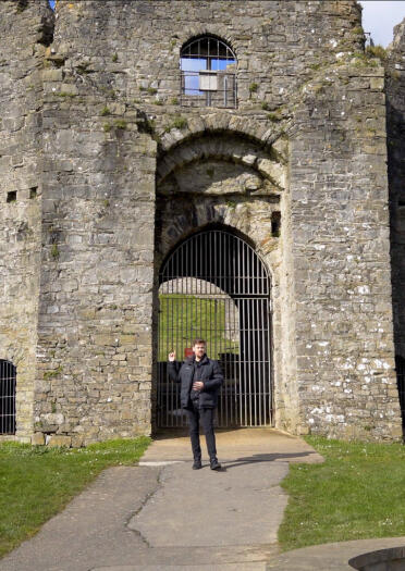 A man stood in a partially ruined castle gateway. 