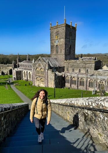 woman walking up steps with St Davids Cathedral in the background,