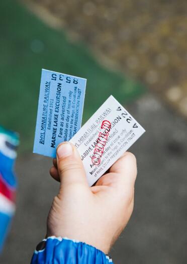 A child holding two cardboard Edmondson train tickets.