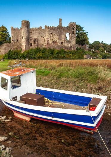 Eine Burgruine mit einem Boot im Vordergrund.