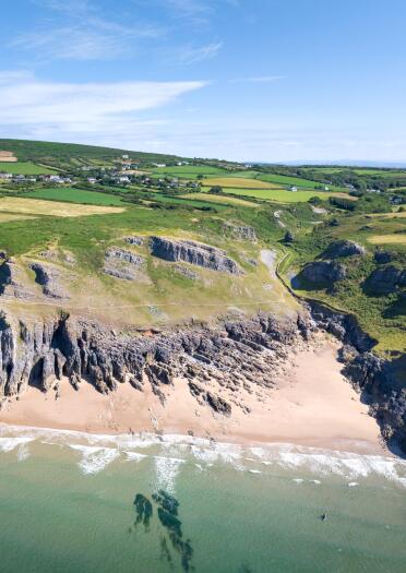 Aerial view of a rocky beach in a cove between cliffs. 