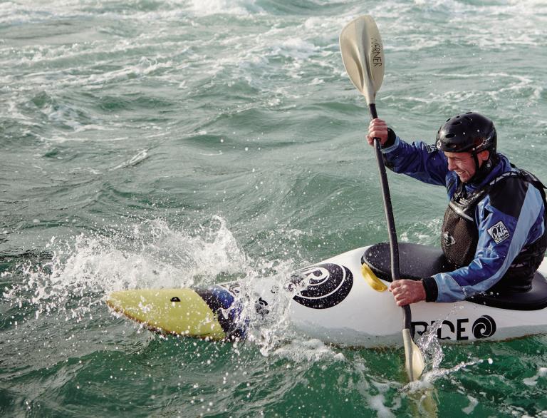A person in a sea kayak off an island.