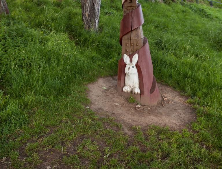 White rabbit sculpture in woods on Alice in Wonderland trail.