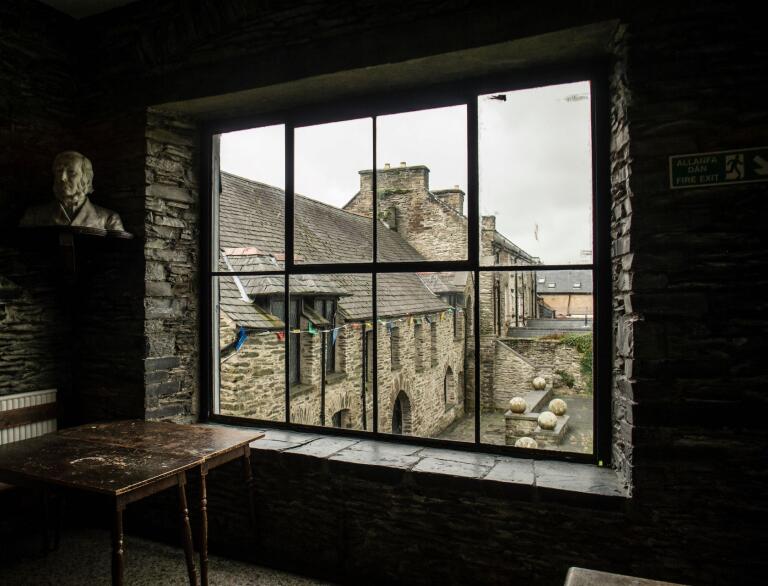 Ausblick aus einem Fenster auf einen kleinen Innenhof mit steinernen Gebäuden drum herum.
